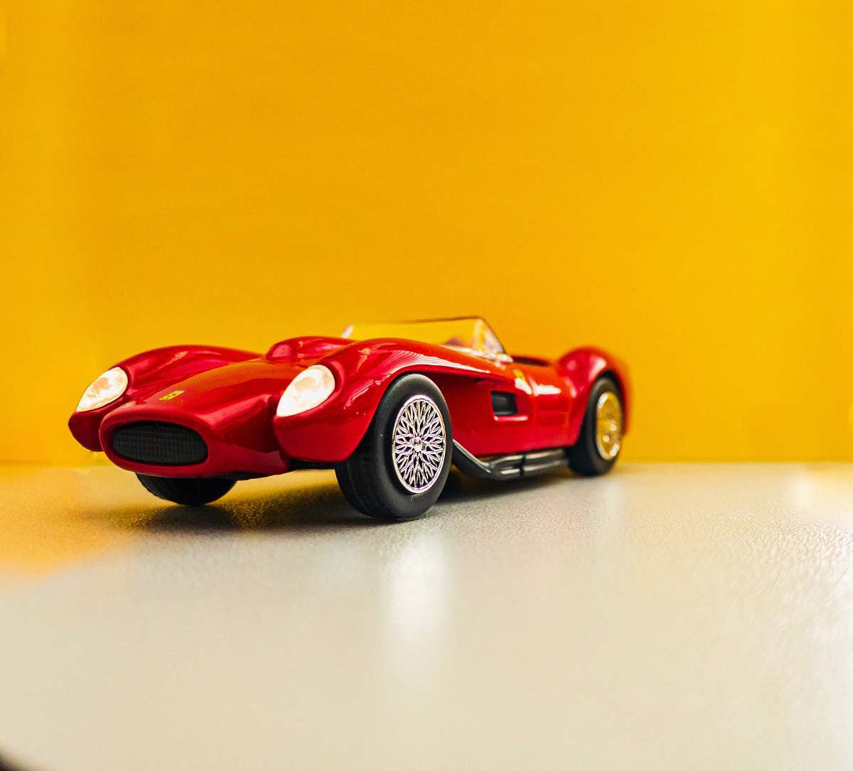 machine red coupe scale model on white surface spoke